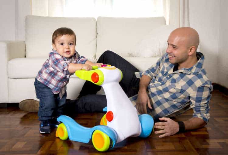 Toddler using a push walker with dad