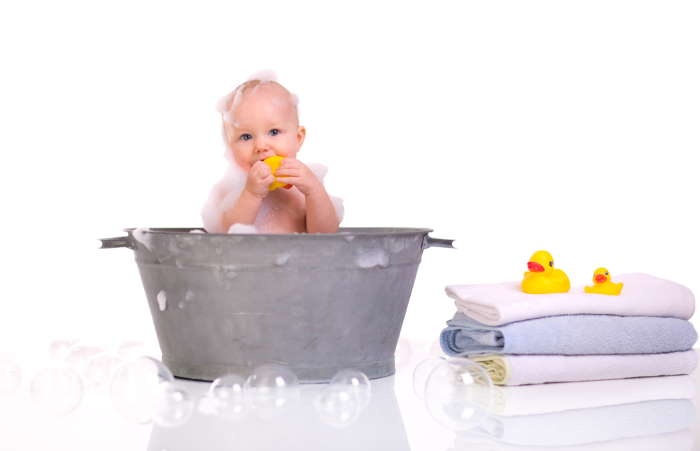 Cute baby girl having bath in a metal tub