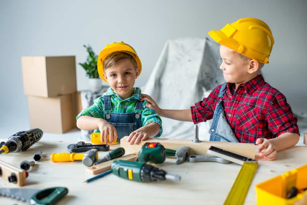 2 kids playing with toy tools on a workbench