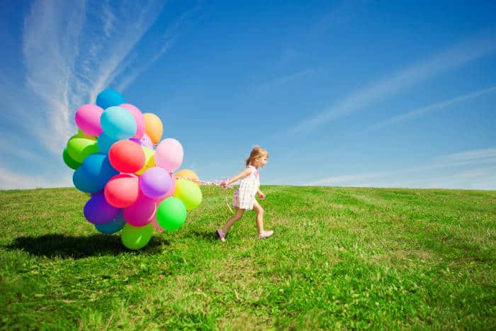 Girl with party ballons in a field
