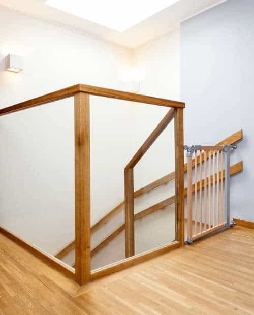 A baby gate at the top of a steep staircase