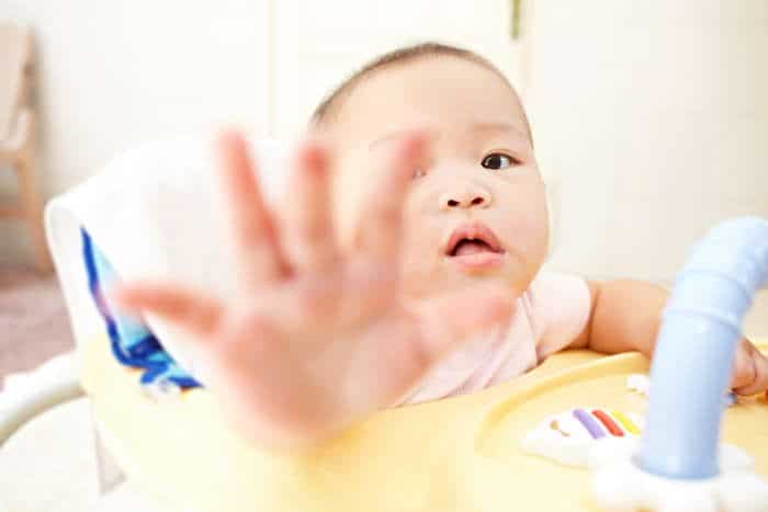 Baby girl trying to reach from within a seated walker