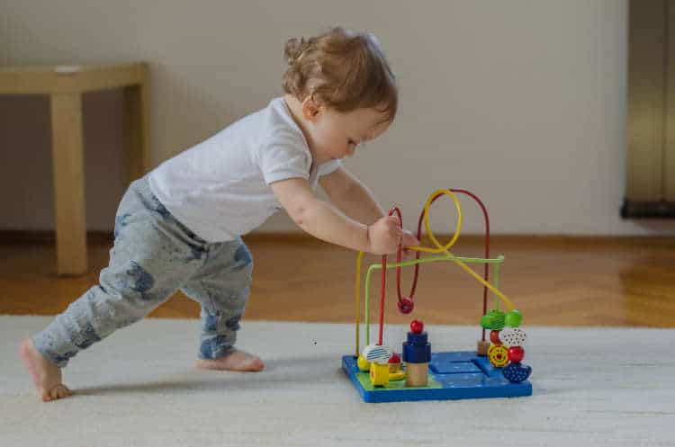 Toddler pushing a toy across carpet