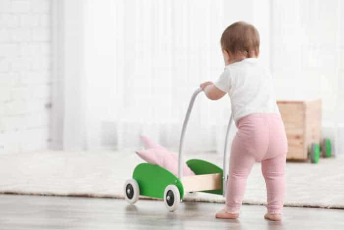 Baby pushing a push walker onto carpet