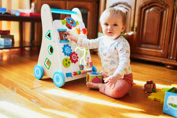 Sitting playing with a push walker that is also an activity center