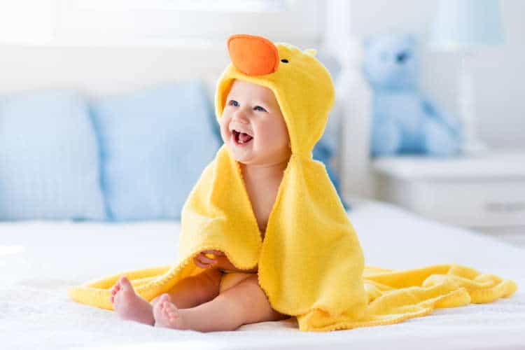 A cute baby in a yellow duck bath towel with a hood