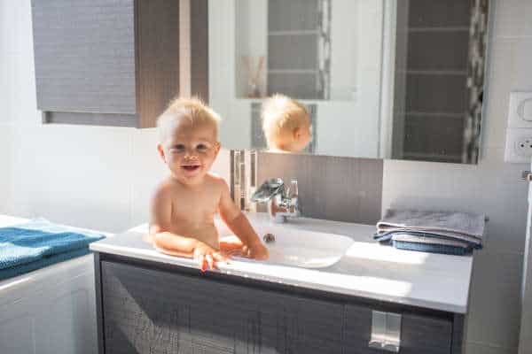 A baby bathing in a sink