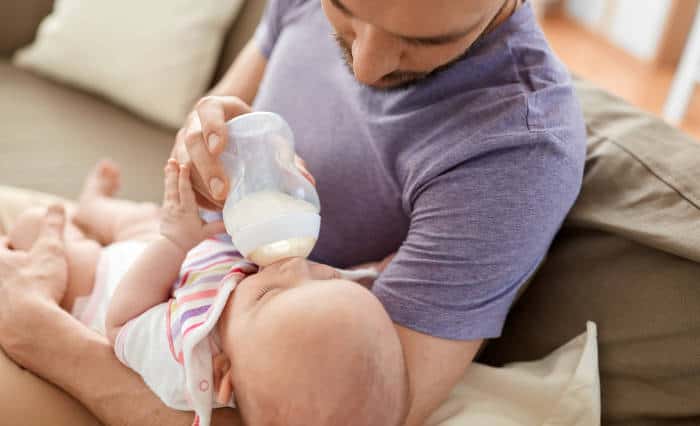 Closeup of dad bottle feeding a baby