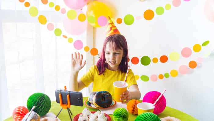 Girl having a virtual birthday party surrounded by decorations and cake