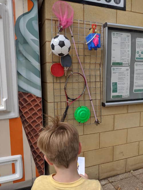 Boy looking at a display of things hanging on a wall
