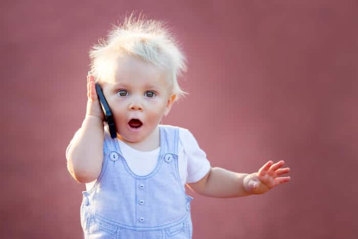 a cute baby with a surprised expression using a cell phone