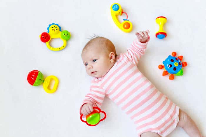 baby surrounded by baby rattles