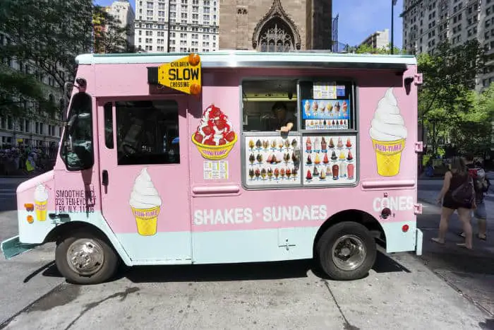 An ice cream truck parked on the sidewalk in new york