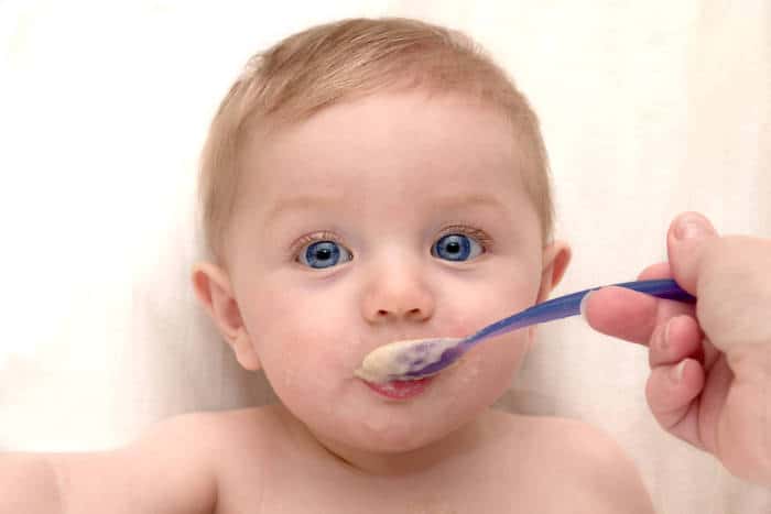 Baby being fed oatmeal on a spoon