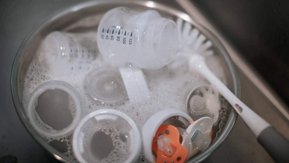 baby bottles and baby bottle brush in washing bowl