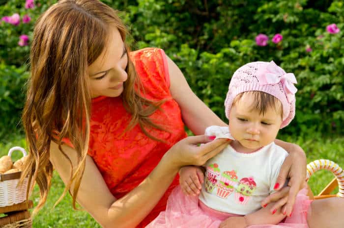 Mother wiping a babies face with a wipe