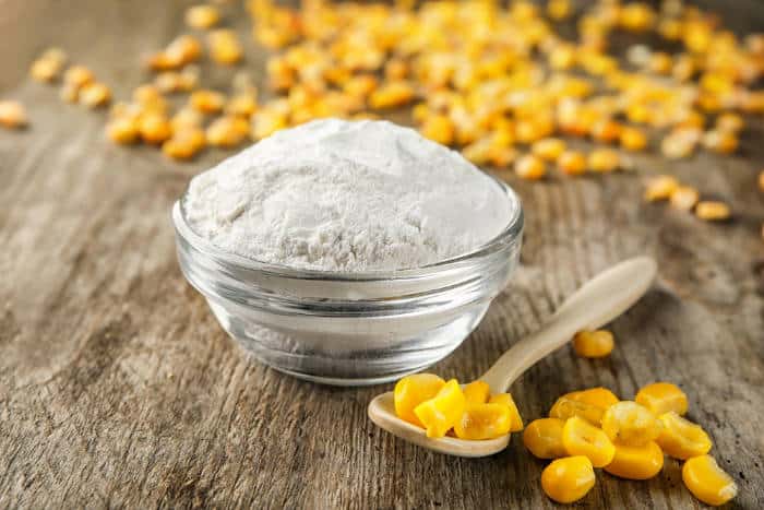 corn kernels and corn starch in a bowl on awooden table