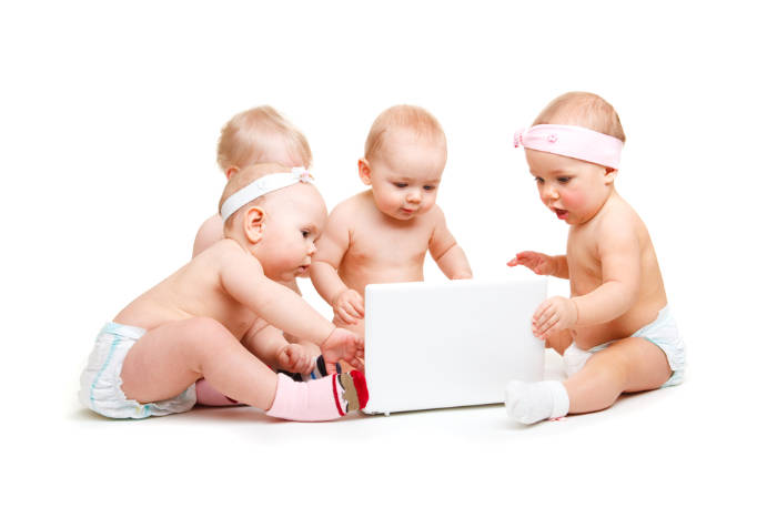 4 toddlers gathered round a laptop computer