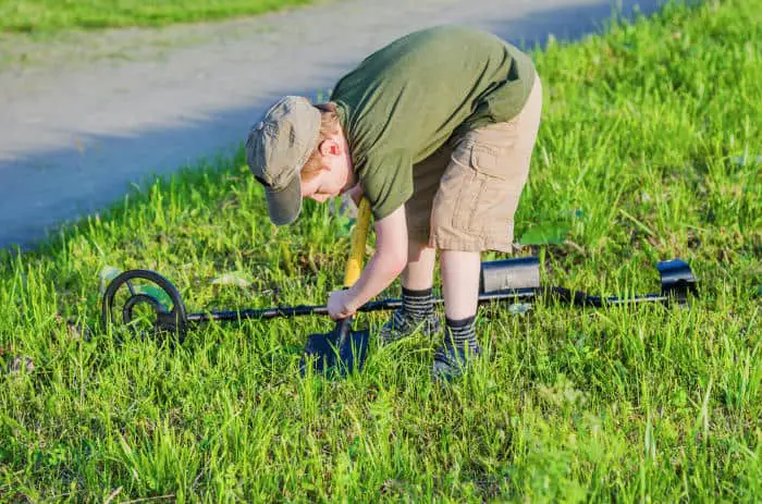 Boy digging for treasure with metal detector