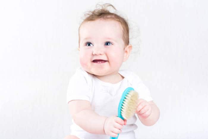 cute baby holding hair brush