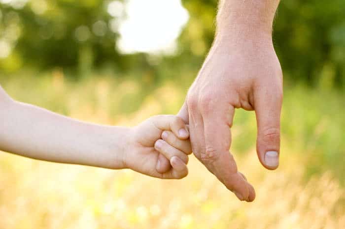 young child holding fathers finger