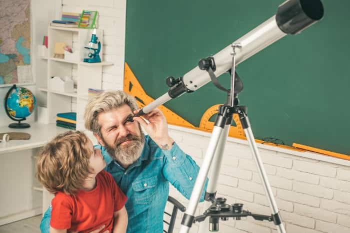 father and son using telescope together