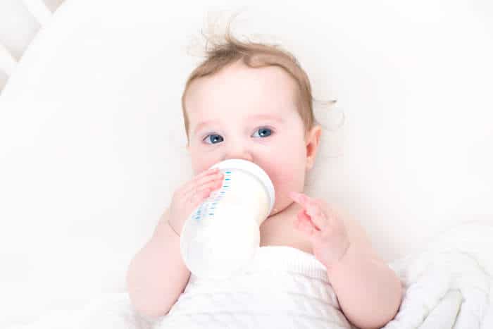 Baby holding own milk bottle and drinking