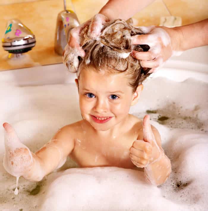 Young girl having hair washed in the bath