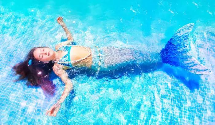 girl dressed as a mermaid floating in the pool