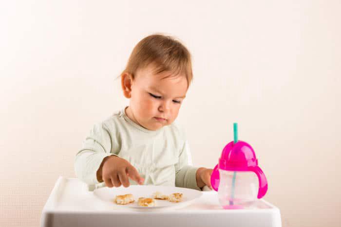 Baby with a straw cup and dinner